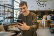© Miljan Živković - young man show cup of coffee while have video call on cellphone