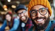 © DKPhoto - A fashionable man wearing a hat and an orange beanie radiates happiness and confidence, providing a sense of warmth in a relaxed social environment filled with friends.