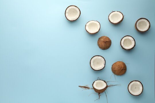 Wall Mural -  - halves of fresh coconuts on light blue background, flat lay. space for text