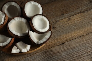 Wall Mural - Pieces of cracked coconuts on wooden table, closeup. Space for text