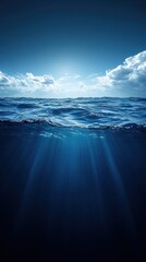 Poster - Captivating ocean view featuring sunlit waves and underwater rays of light beneath a blue sky with clouds serene seascape