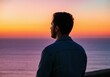 © Rizka - Man Watching Sunset Over Ocean Coastline