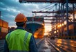 © jamal - Port worker in safety vest and hard hat looks out over harbor basin filled with containers at evening light. Golden hour atmosphere highlights industry scene.