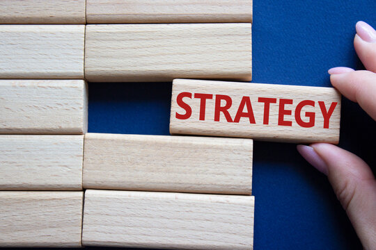 Strategy symbol. Concept word Strategy on wooden blocks. Businessman hand. Beautiful deep blue background. Business and Strategy concept. Copy space.