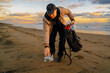 © Bohdan - Volunteer saving sea from plastic pollution. Man cleaning on the beach