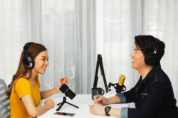 Smiling radio influencer host wearing headphone interviewing woman speaker sharing information to listeners on social media online website live streaming channel at morning at studio record. Infobahn.