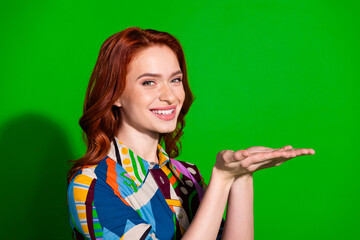 Wall Mural - Happy woman in colorful shirt with vibrant red hair posing against green studio background