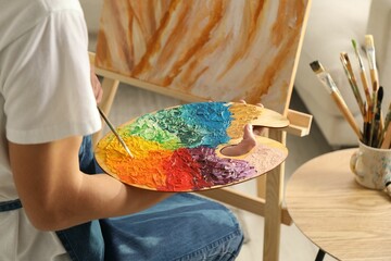 Wall Mural - Man with palette and paintbrush drawing picture indoors, closeup