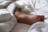 Person feet under blanket on the bed