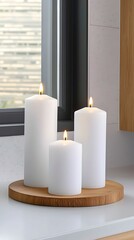 Wall Mural - Three elegant white candles with flames, arranged on a wooden tray, placed by a window, creating a cozy and serene ambiance.