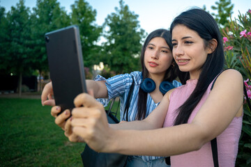 Two young women are happily taking a selfie with their cell phone