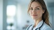 © AlfaSmart - Female young doctor smiling in hospital setting with stethoscope