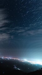 Wall Mural - beautiful panoramic view of city at night with starry sky above, time lapse view