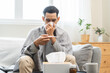 © KMPZZZ - Sick, influenza asian young man have fever blowing nose, sneezing in tissue, holding thermometer for check measure body temperature, ill while rest at home. Health care with disease, pandemic virus