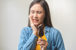 © KMPZZZ - Face expression suffering from sensitive teeth and cold, asian young woman touching cheek, hurt or pain eating ice cream with chocolate. Toothache molar tooth, dental problem isolated on background.