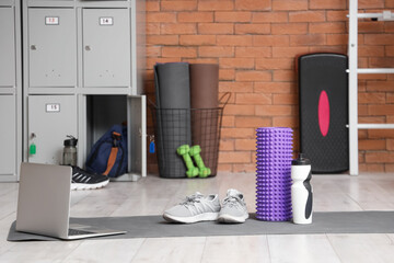 Wall Mural - Foam roller with water bottle, sneakers and laptop on mat at gym