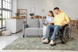 © Pixel-Shot - Young man in wheelchair and his girlfriend with laptop at home