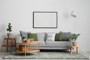 Wall Mural - Cozy sofa, coffee table and big blank photo frame on white wall in room