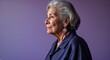 © sevenSkies - Elderly Hispanic woman in plain purple background navy dress side view portrait