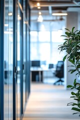Poster - Modern office interior featuring glass partition walls, a lush green plant in the foreground, and empty workspaces in the background