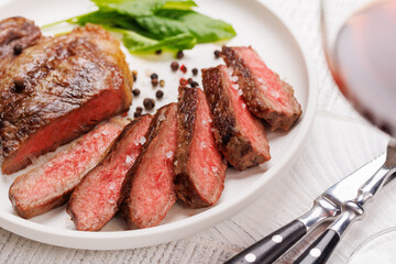 Poster - A perfectly cooked sliced striploin steak with a juicy, tender texture, served alongside a glass of rich red wine