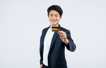 Wall Mural - Portrait of young Asian business man holding bank card and posing on white background