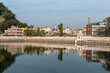 © Balaji - Shravanabelagola's tranquil lake reflecting the colorful buildings and hills in the distance during a clear day
