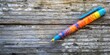 © Gular - Vibrant multicolored pen on rustic weathered wooden background with ample copy space, positioned to the left, showcasing rich textures and patterns