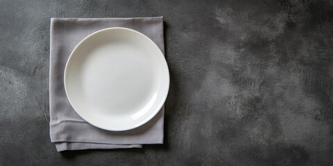 Aufkleber - Blank white plate centered on a soft grey napkin against a textured dark backdrop captured from a top view perspective for elegant table setting.