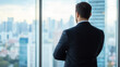 © Alexander - A seasoned entrepreneur in a dark business suit, standing with arms folded and a serious expression, contemplating a difficult decision in front of a window overlooking a cityscape