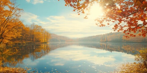 Fototapete - Serene autumn landscape with vibrant orange and yellow leaves framing a peaceful lake reflecting the clear blue sky and soft sunlight.