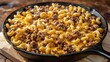 © meristock - Cheeseburger macaroni skillet with golden melted cheese and pasta in a black skillet on a wooden surface featuring ground beef and elbow macaroni