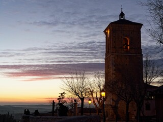 Wall Mural - Romantic sunset next to the bell tower of an old church under a sky covered with golden clouds