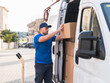 © Martí Rosselló - Delivery driver organizing packages in a delivery van. Delivery driver concept in a van. Man in blue uniform arranging boxes inside a delivery vehicle, representing logistics and shipping.