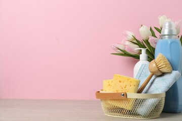 Wall Mural - Spring cleaning. Detergents, supplies and tulips on white wooden table against pink background, space for text