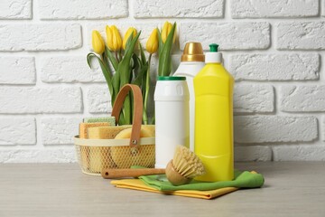 Wall Mural - Spring cleaning. Detergents, supplies and tulips on white wooden table against brick wall