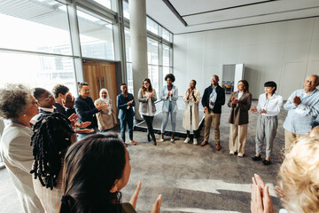 Wall Mural - Diverse team in a circle participating in a teambuilding exercise in a modern office space