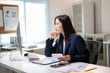 © Wasana - A woman in a business suit sits at a desk with a computer monitor