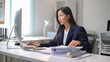 © Wasana - A woman is sitting at a desk with a computer monitor in front of her