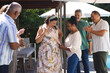 © Wavebreak Media - Diverse senior friends celebrating outdoors, woman wearing sash smiling while others clap and cheer