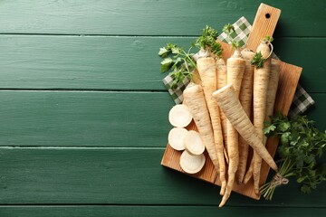 Wall Mural - Parsley roots and leaves on green wooden table, top view. Space for text