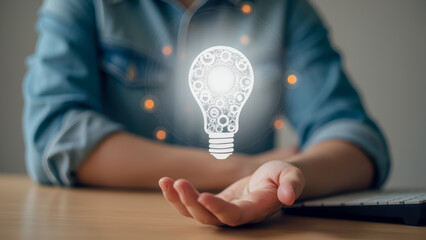 Poster - Woman with digital lightbulb graphic symbolizing innovative ideas, creativity, and inspiration in a modern workspace environment