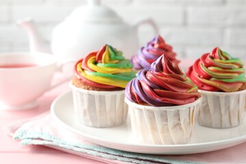 Wall Mural - Delicious cupcakes with colorful cream and tea on pink table, closeup