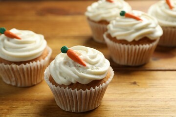 Wall Mural - Delicious carrot cupcakes on wooden table, closeup