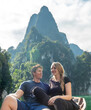 © Allison - Couple enjoys a boat ride on a serene lake surrounded by towering mountains in the afternoon