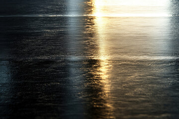 Poster - A dark, textured surface reflects light, creating a gradient of golden hues.
