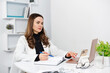 © Oksana Klymenko - Telemedicine. Female doctor wearing uniform taking notes in medical journal, filling documents, patient illness history, looking at laptop screen. Online doctor on laptop.