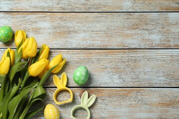 Wall Mural - Easter eggs, bunny figures and beautiful tulips on wooden background, flat lay. Space for text