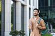 © Liubomir - Student walking outside university campus with books in hand. Young man with backpack in casual clothes, happy and smiling.