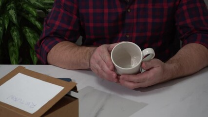 Wall Mural - The man examines the damage on the mug, takes a picture of it on his smartphone and issues a refund online in the mobile application.